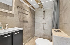 A modern bathroom with a shower, toilet, and vanity.