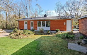 Eine Holzhütte mit geneigtem Dach, einer Veranda und einem kleinen Garten.