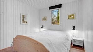 A bedroom with a wooden bed, white walls, and a window with a view of trees. - Gorgeous home in Ansager with WiFi (Ansager)