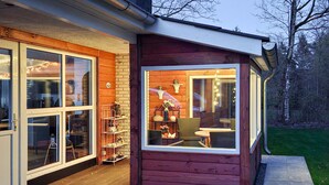 A wooden cabin with a glass door, a small porch, and a chair outside. - Gorgeous home in Ansager with WiFi (Ansager)