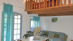 A room with a dining table, chairs, a sofa, a wooden ceiling, and a painting on the wall.