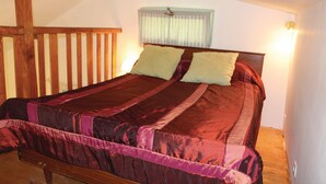 A bed with a wooden headboard, two pillows, and a striped bedspread.