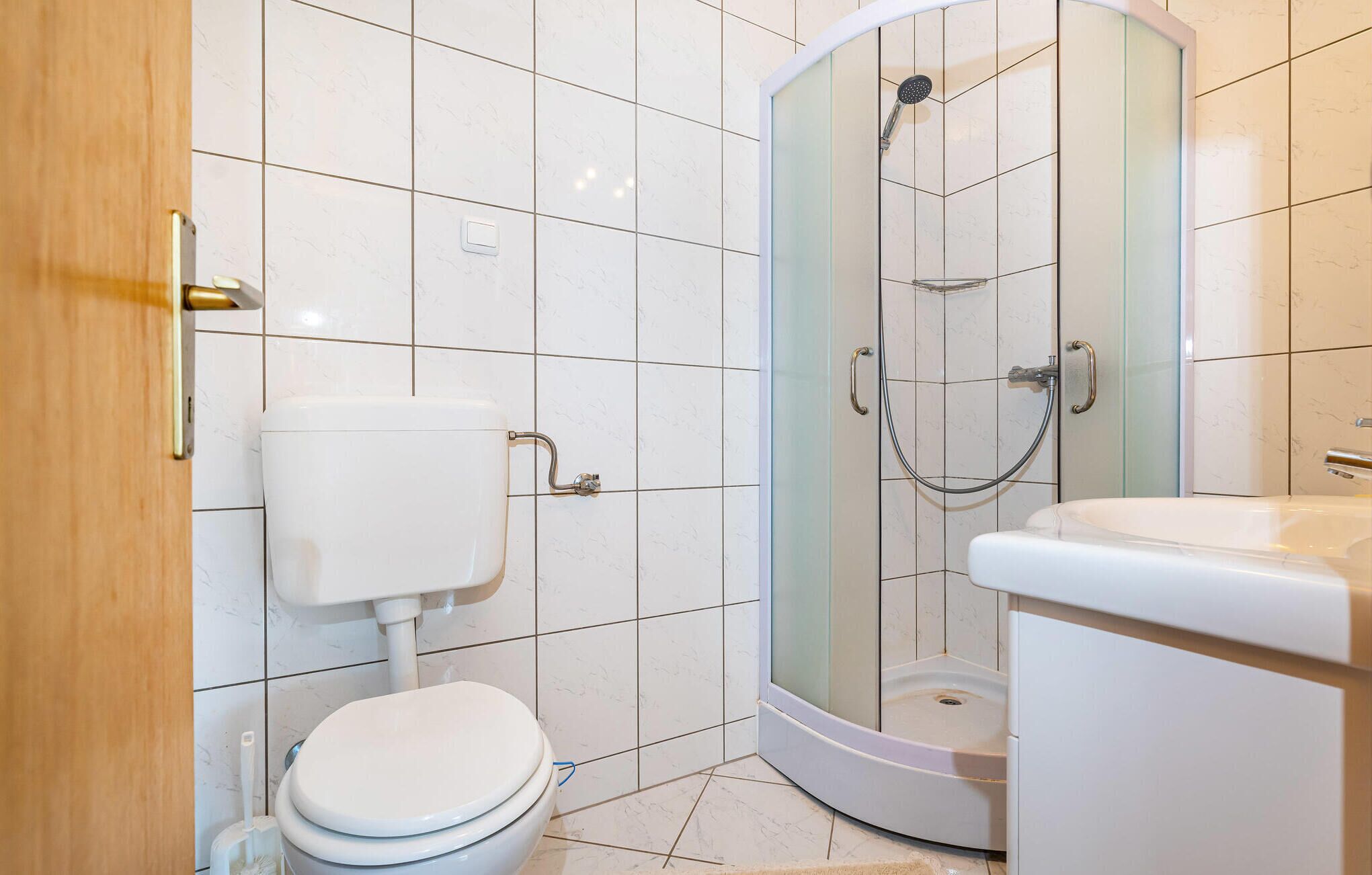 Kylpyhuone, jossa on wc, suihkukaappi ja pesuallas.