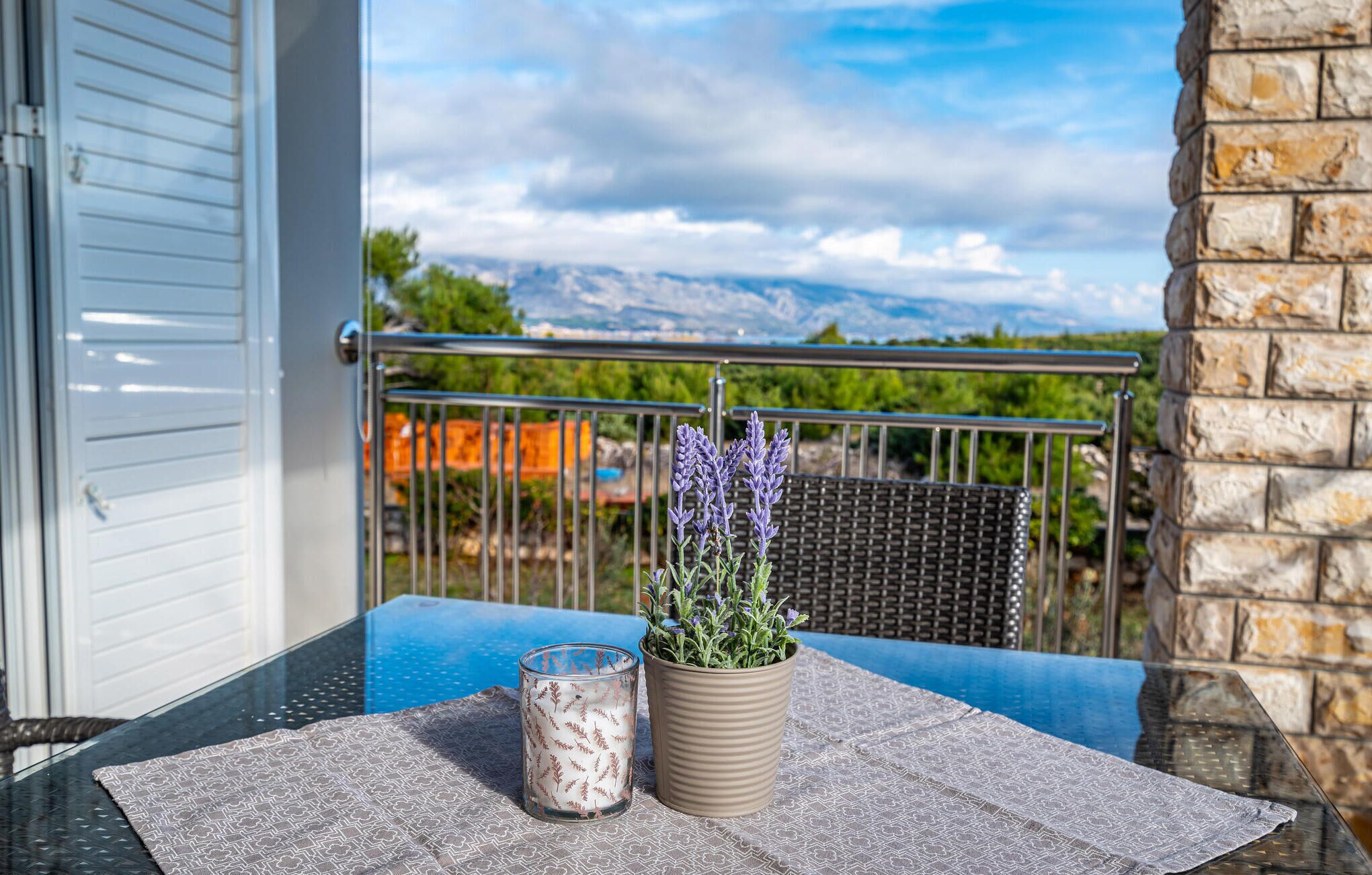 En balkon med et bord, en potte lavendel og et lys.