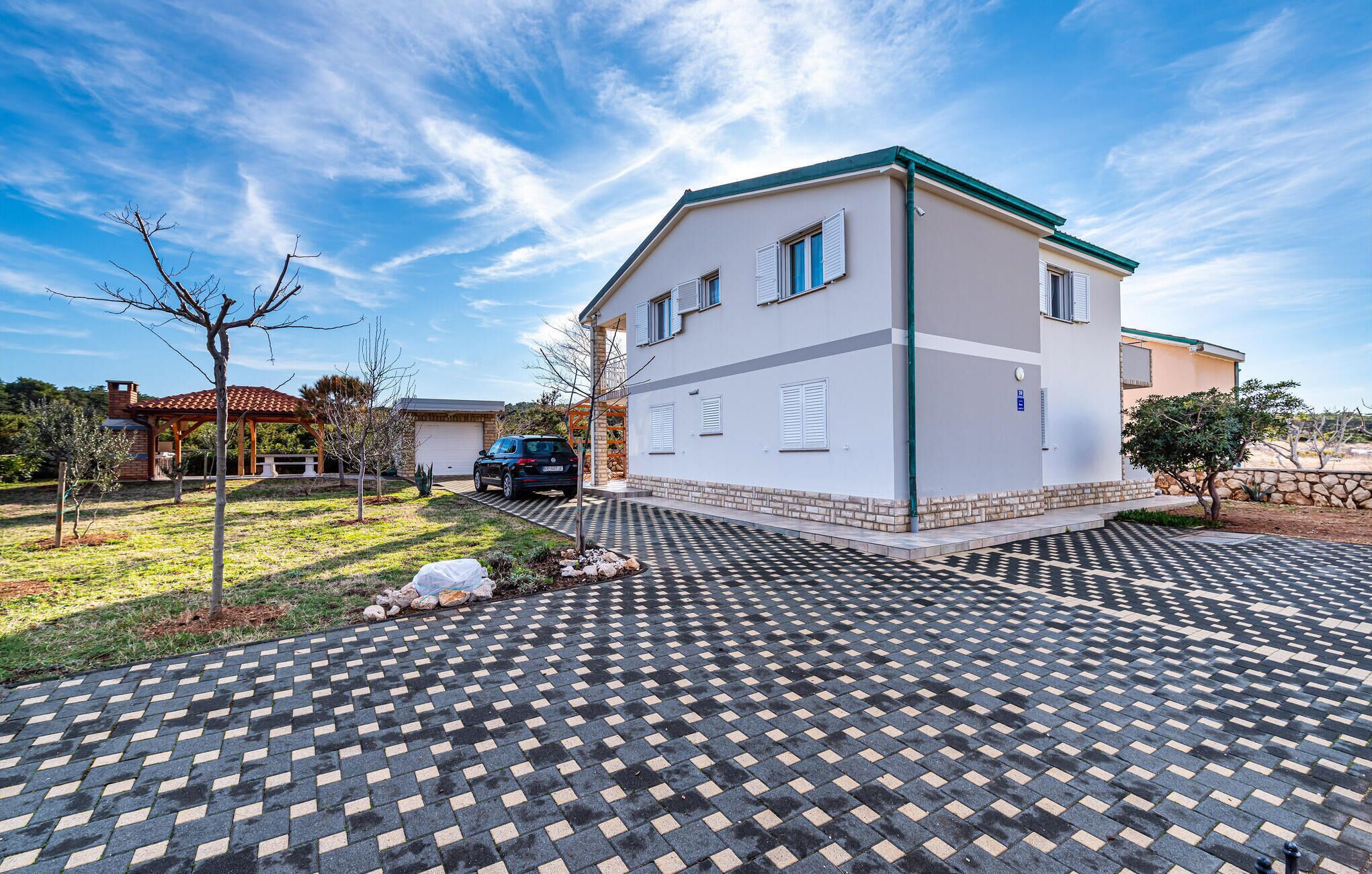 A modern two-story house with a paved driveway and a small garden area.
