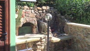 A stone-built outdoor kitchen with a pizza oven, a sink, and a metal rack. - 2 bedroom gorgeous home in Costa Rei (Costa Rei)