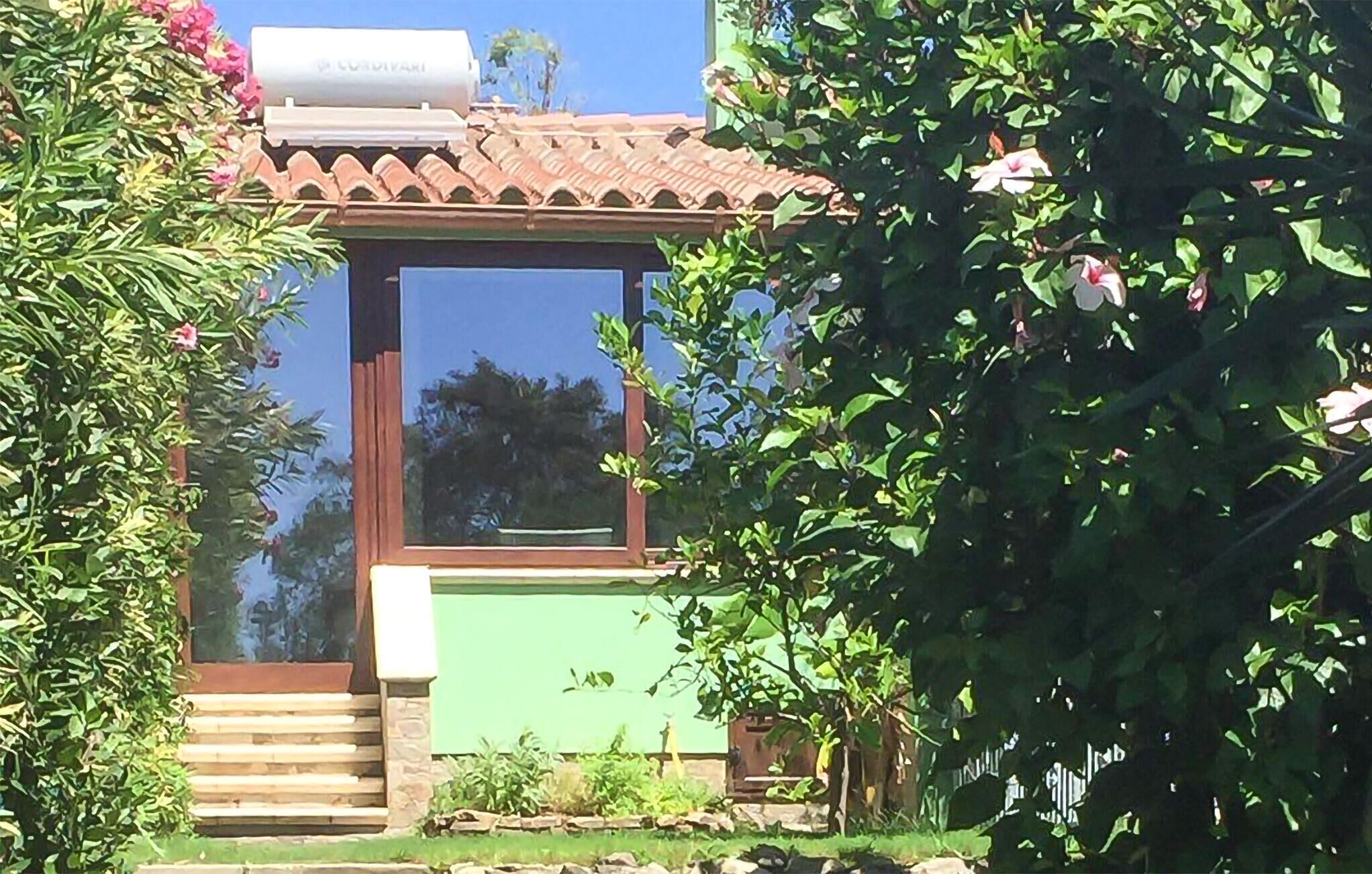 Ein Haus mit grüner Fassade, einem Ziegeldach und einem Fenster mit Blick zum Himmel.