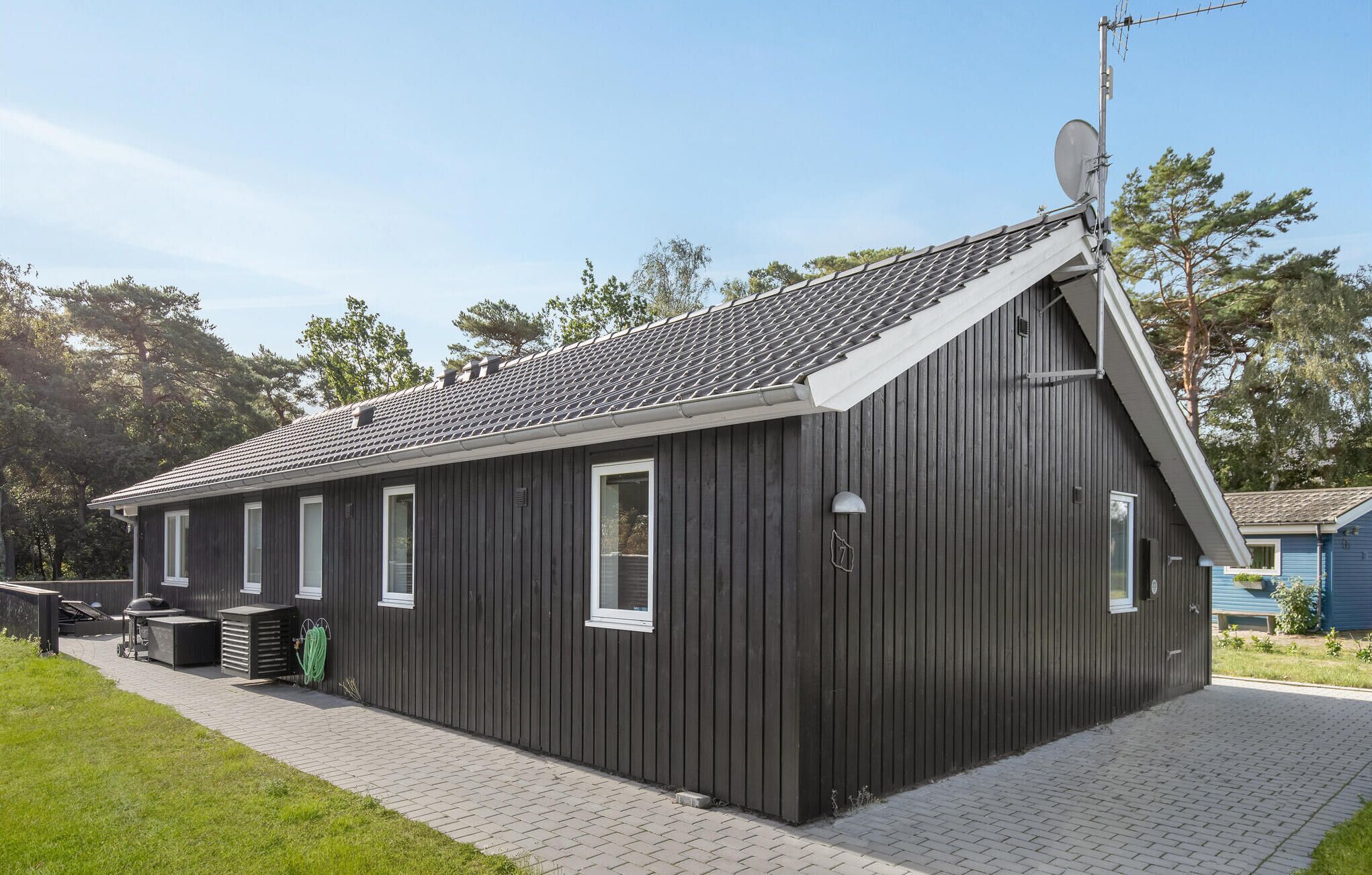 Un bâtiment d’un seul étage, à l’extérieur sombre, avec un toit en pente et une antenne parabolique.