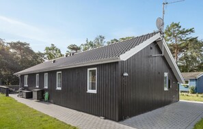 A single-story building with a dark exterior, a sloped roof, and a satellite dish. - Stunning home in Nexø with sauna (Nexø)