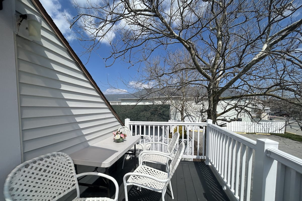 A covered outdoor deck with white railings and a table with chairs.