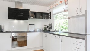 Een moderne keuken met witte kastjes, roestvrijstalen apparatuur en een raam dat voor daglicht zorgt.