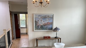 A dining area with a wooden table, teal chairs, a chandelier, a painting, and a lamp.