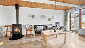 A living room with a wood-burning stove, a sofa, a table, and a large window. - Awesome apartment in Hasle with WiFi (Hasle)