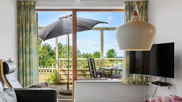 A modern living room with a large window, a TV, and a dining area with outdoor furniture. - Awesome apartment in Hasle with WiFi (Hasle)