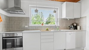 A modern kitchen with white cabinetry, a built-in oven, a dishwasher, and a window with blinds. - Awesome apartment in Hasle with WiFi (Hasle)