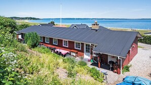 A red building with a flat roof, a covered outdoor seating area, and a view of the sea. - Lovely home in Fredericia with WiFi (Fredericia)