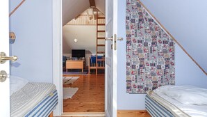 Ein Schlafzimmer mit zwei Betten, Holzboden, Fernseher und Schreibtisch mit Stuhl.