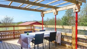 Eine Außenpatio mit Holztisch und Stühlen, einer Glasüberdachung und Blick auf die umliegende Landschaft.