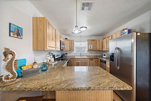 Enjoy cooking in this well-equipped kitchen with a granite countertop, stainless steel appliances, and wooden cabinetry.