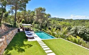 Relax by the serene pool surrounded by lush greenery and a tranquil atmosphere.