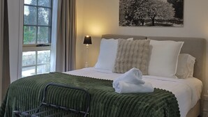 Un dormitorio con una cama, una ventana, aire acondicionado de pared y un cuadro con árboles.