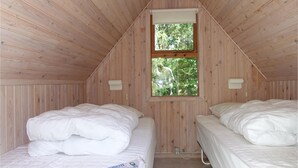 A small, wooden-paneled room with two beds, each with white bedding. There is a window providing a view of greenery outside. - Stunning home in Aakirkeby with WiFi (Aakirkeby)