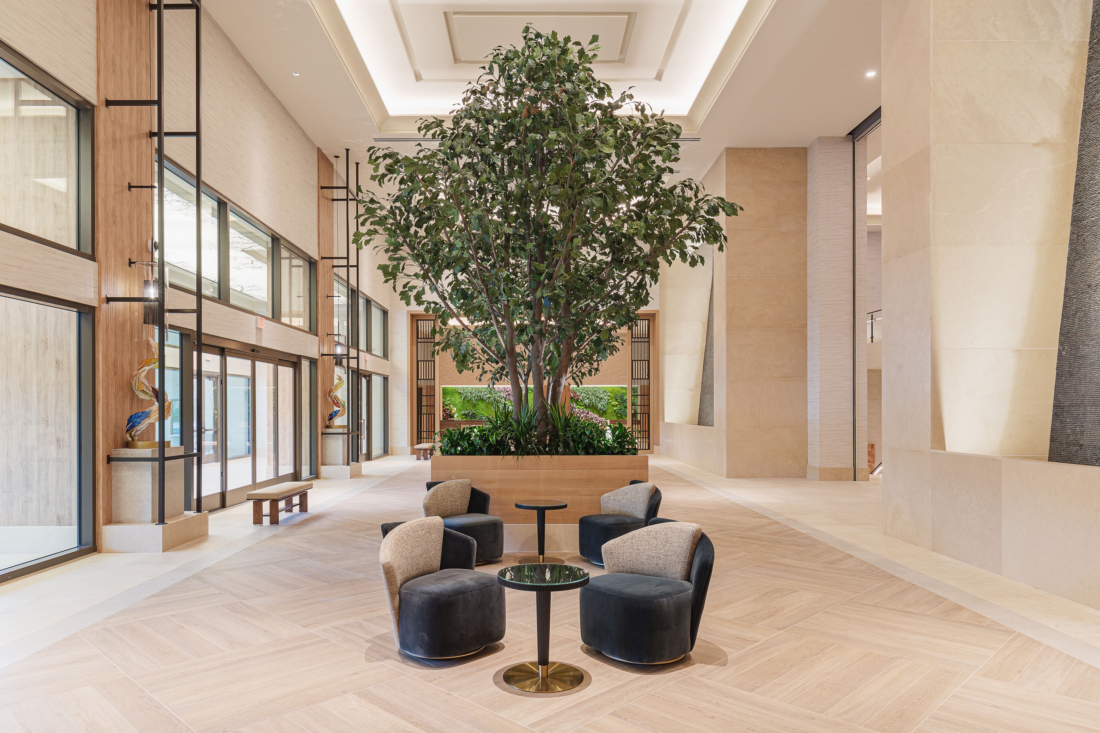 Un vestíbulo espacioso con un gran árbol artificial, asientos cómodos y un diseño moderno.