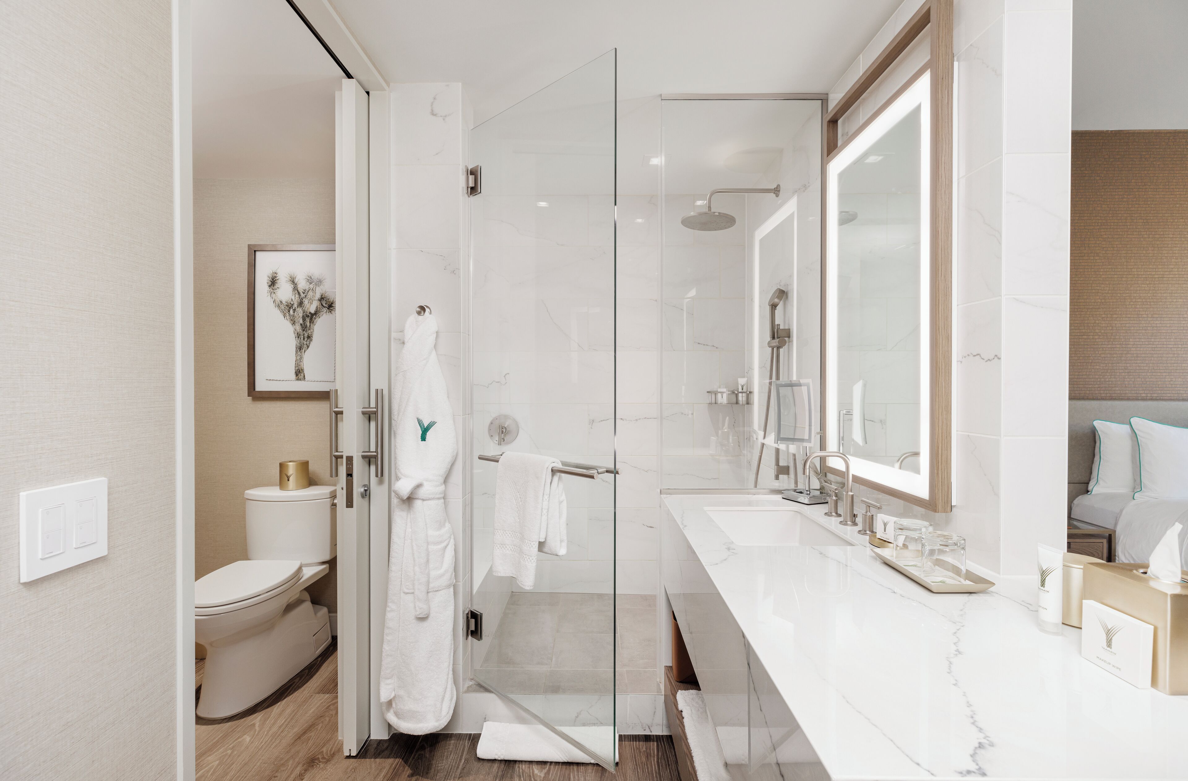 A modern bathroom with a glass shower enclosure, a white toilet, a marble sink, and a large mirror.