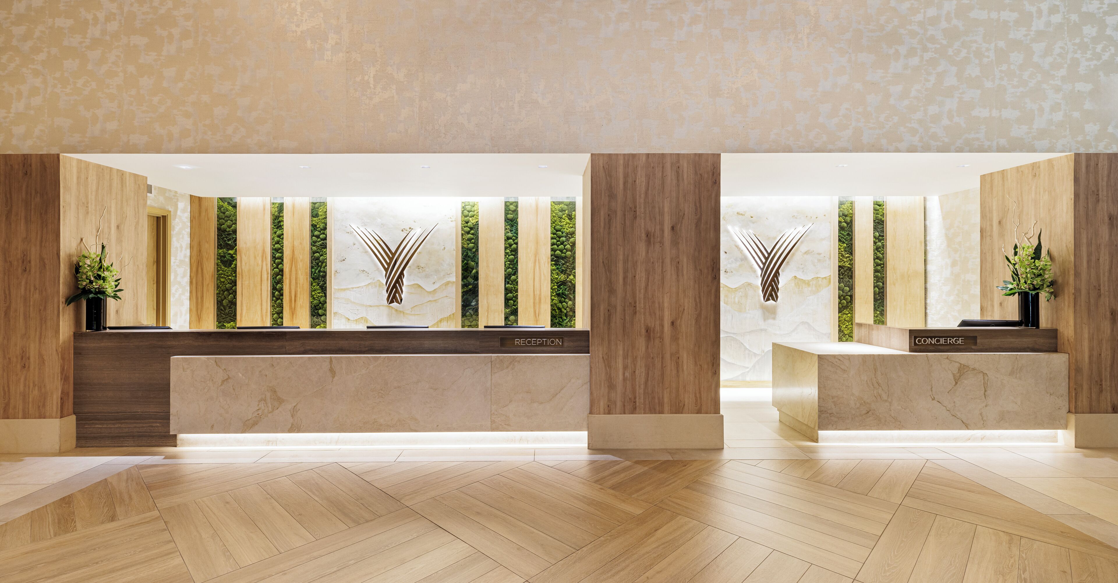 A reception area with a marble counter, wooden accents, and vertical greenery.