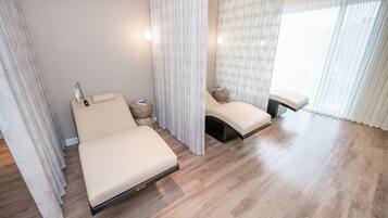 Une chambre moderne avec un grand lit, des tables de chevet et une fenêtre ornée de rideaux légers.