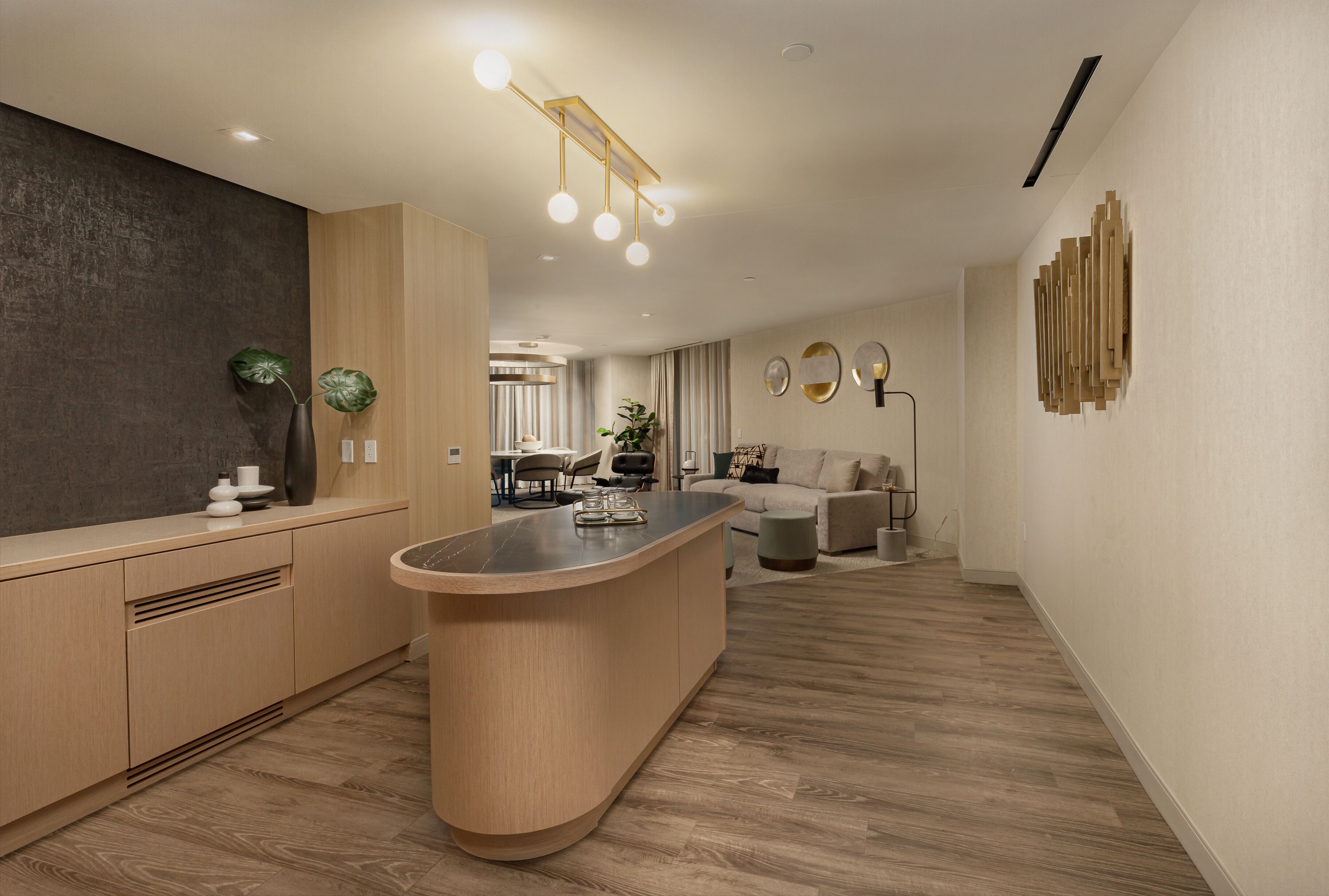 A modern kitchen with a central island, wooden cabinetry, and a dining area in the background.