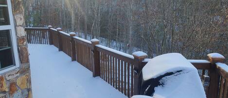 Ein mit Schnee bedeckter Balkon mit einer Steinmauer und einem Hollerdacht.