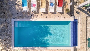 A rectangular swimming pool with a tiled deck surrounding it.