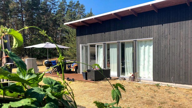 A modern building with large glass doors and a deck area with outdoor furniture. - Amazing home in Köpingsvik with WiFi (Köpingsvik)