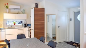 A modern kitchen with white cabinets, a wooden accent wall, a dining area with a table and chairs, and a view of a snowy landscape through the window. - Amazing home in Köpingsvik with WiFi (Köpingsvik)
