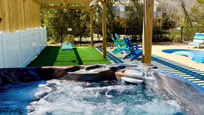 A hot tub area with a wooden pergola overhead, a pool, and a fenced deck. - Short Steps to Beach! Private Pool! Hot Tub! Linens Included! Family Favorite. (Kitty Hawk)