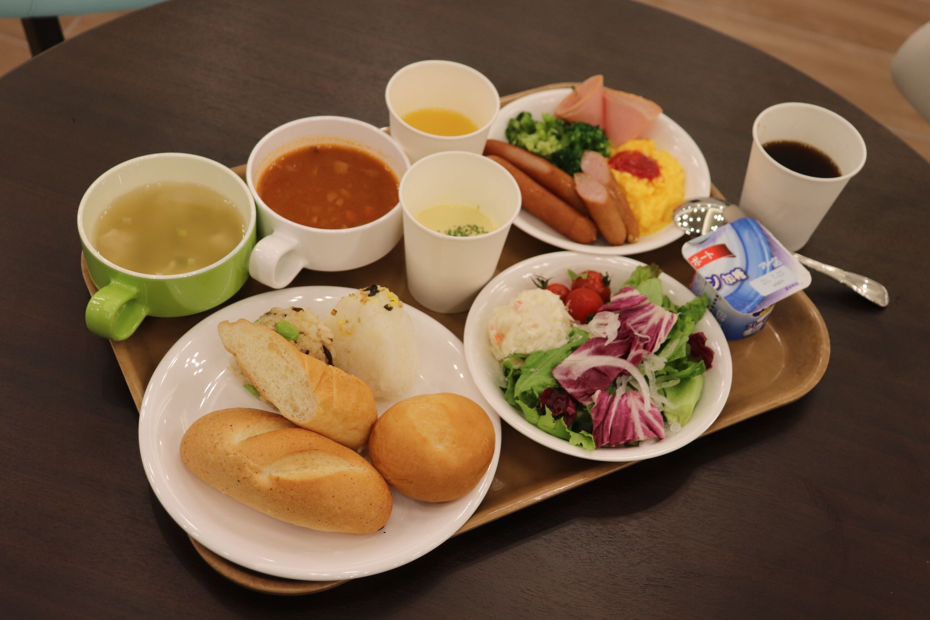 A tray with soup, hot dogs, salad, bread, and condiments.