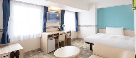 Una habitación de hotel con cama, escritorio, silla, mesita pequeña, pantuflas, espejo y televisión.