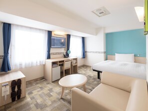 A hotel room with a bed, a desk, a chair, a small table, slippers, a mirror, and a television. - TOYOKO INN Tsubame-Sanjo Ekimae (Tsubame)