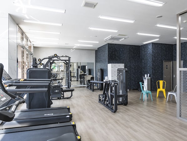 A modern gym with treadmills, weight machines, and free weights.