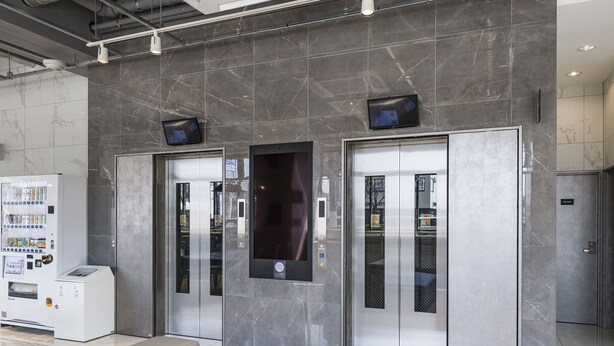 Un vestíbulo moderno con máquina expendedora, dos ascensores y puerta privada.