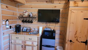 Kompakti keittiö, jonka seinät ovat puuta, ja jossa on sisäänrakennettu mikroaaltouuni, kahvinkeitin, pesuallas ja pieni jääkaappi.