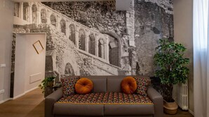 A living room with a sofa, a potted plant, and a wall mural.