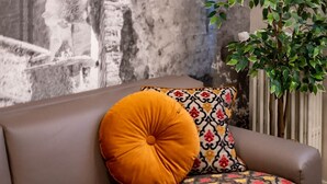 A brown leather sofa with a patterned cushion and a round orange cushion.
