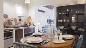 Une cuisine moderne avec une table à manger ronde, des chaises bleues et un meuble noir contenant de la verrerie.