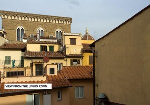 A view from a living room overlooking a row of terracotta-tiled buildings with arched windows and a dome structure.