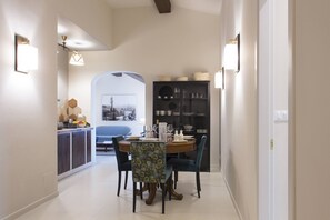 A dining area with a round table, chairs, and a black cabinet with glassware.