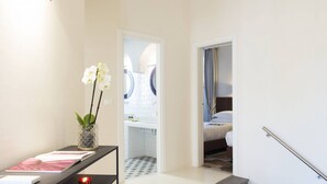 Une chambre d’hôtel avec un lit, un bureau agrémenté d’un vase de fleurs et un escalier.