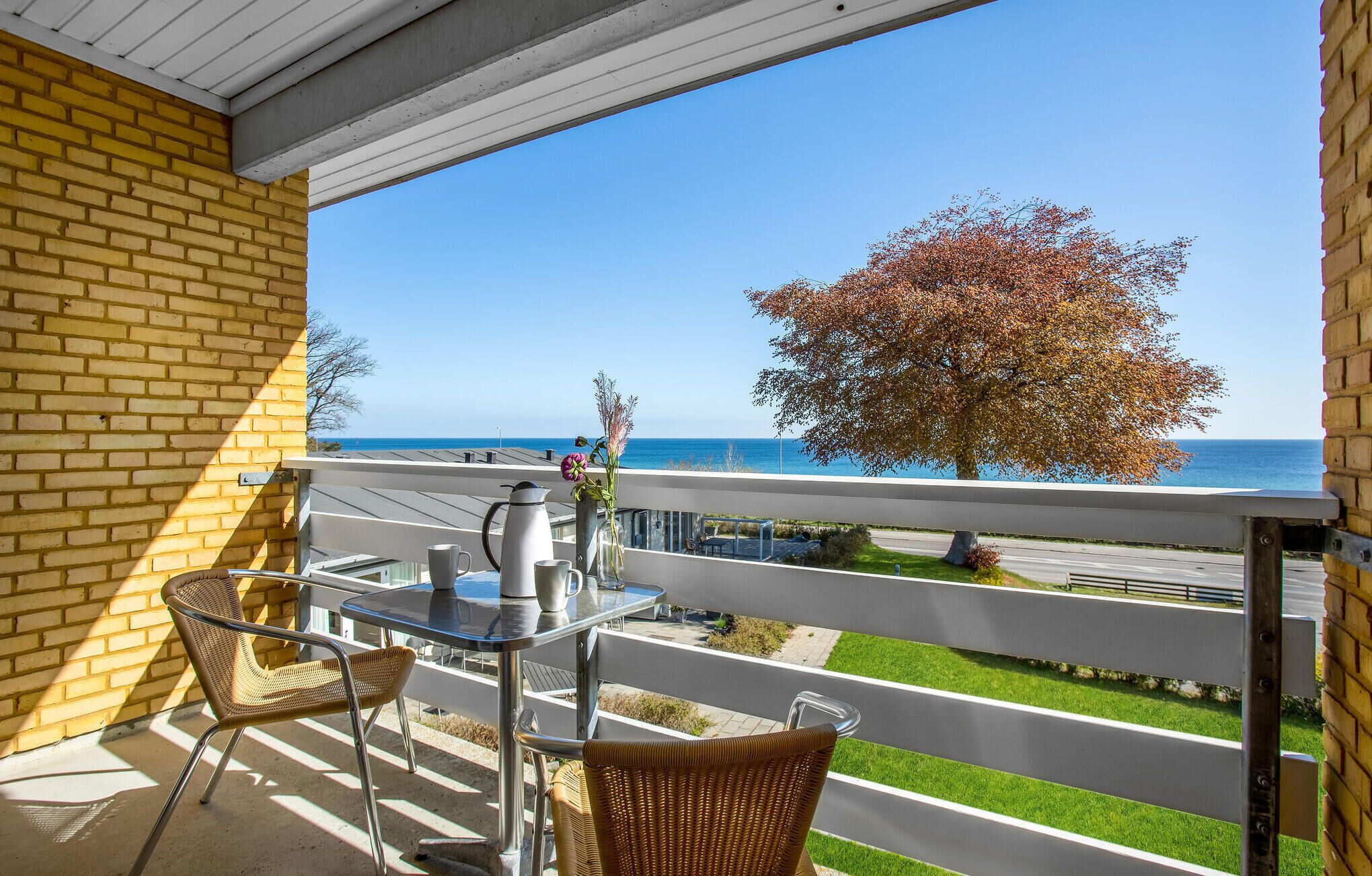 A balcony with a table, chairs, and a view of the sea.