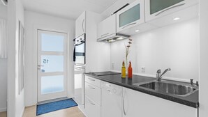 Une cuisine moderne avec des meubles blancs, un plan de travail noir et des appareils en acier inoxydable.